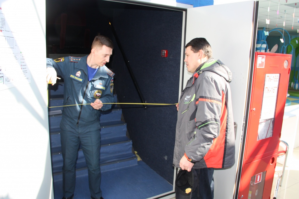 Начальник службы безопасности ТРЦ «Солнечный»Андрей Исайчев помогает инспектору ОлегуШабашову замерять ширину выхода из кинозала